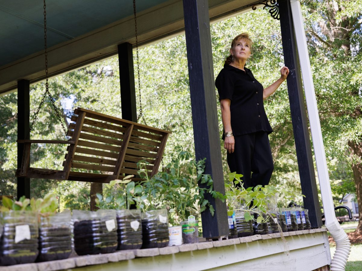 Jamie White on the porch of her Gray's Creek home with plants in water bottles