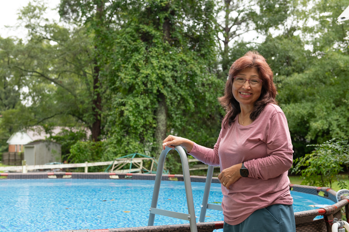 Mariel Biebel stands in front of an above-ground pool with ladder. 