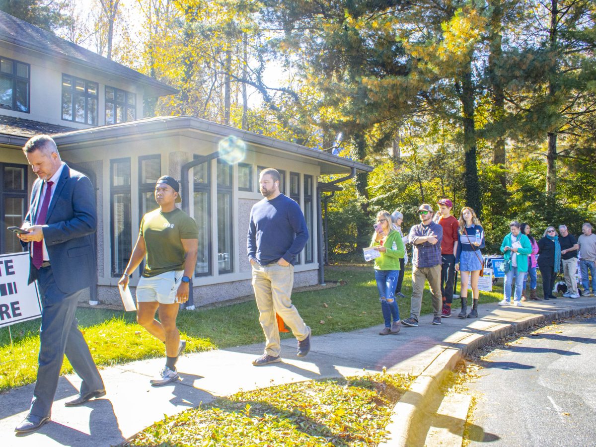 A sign says "vote here" and people wait in line